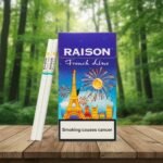 บุหรี่ Raison French Line Blue กล่องสีน้ำเงินลายหอไอเฟลและพลุไฟ วางคู่กับมวนบุหรี่สลิมบนพื้นไม้