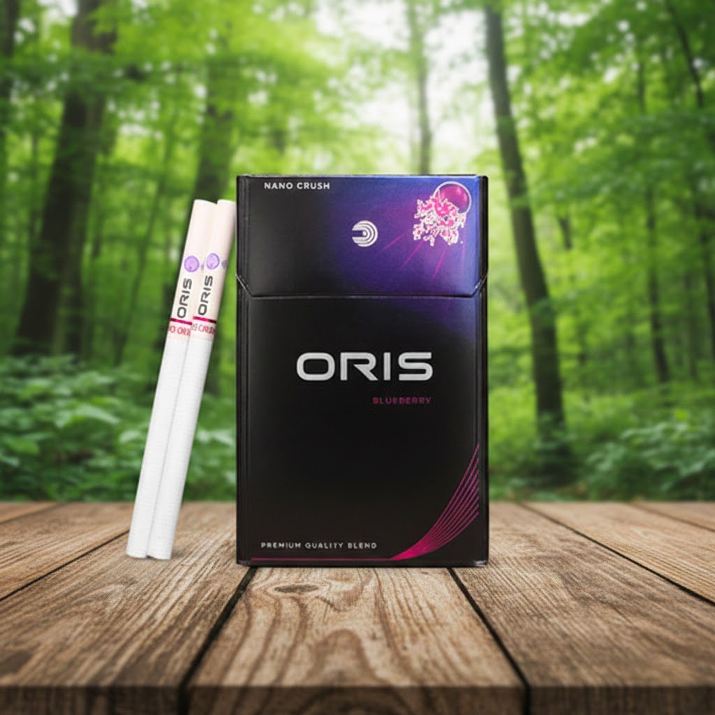 บุหรี่ Oris Nano Crush Blueberry กล่องสีดำแถบม่วง วางคู่กับมวนบุหรี่นาโนสลิมบนพื้นโต๊ะไม้