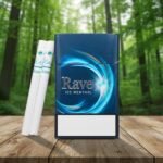 ซองบุหรี่ Rave Ice Menthol สีน้ำเงินดีไซน์ทันสมัย วางบนโต๊ะไม้ท่ามกลางบรรยากาศป่าไม้เขียวขจี