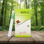 ซองบุหรี่ Oris Paan ดีไซน์สีเขียวขาว วางบนโต๊ะไม้กลางป่าธรรมชาติ