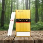 ซองบุหรี่ Napoli Gold สีทองดีไซน์พรีเมียม วางบนโต๊ะไม้ท่ามกลางธรรมชาติ