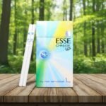 ซองบุหรี่ ESSE Change Up 1mg ดีไซน์สีรุ้งพาสเทลสวยงาม พร้อมมวนบุหรี่ซุปเปอร์สลิม 2 มวน วางบนโต๊ะไม้กลางสวนป่า