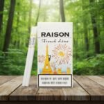 ซองบุหรี่ Raison French Line White ดีไซน์หอไอเฟลและมวนบุหรี่สลิมวางบนโต๊ะไม้ฉากหลังป่า