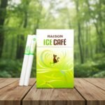 ซองบุหรี่ Raison Ice Cafe สีเขียวอ่อนลายแมว วางคู่กับมวนบุหรี่บนโต๊ะไม้ฉากหลังเป็นป่าธรรมชาติ