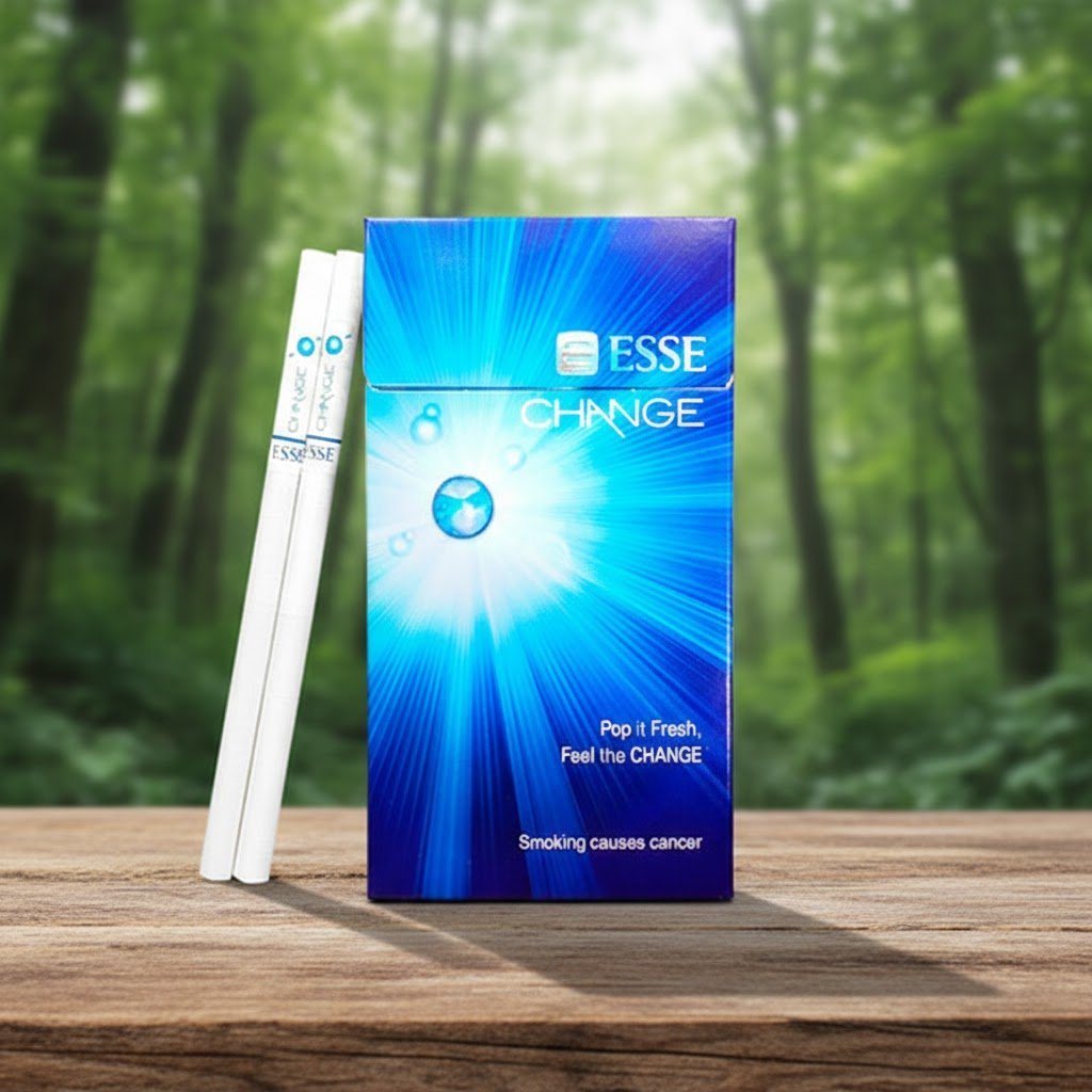 ซองบุหรี่ ESSE Change 4mg สีฟ้าลายรัศมีแสงสว่าง วางคู่กับมวนบุหรี่ Superslims บนโต๊ะไม้ฉากหลังป่า