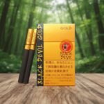 ซองบุหรี่ Black Devil Gold และมวนบุหรี่สีดำขอบทอง วางบนโต๊ะไม้ในบรรยากาศป่าไม้สีเขียว