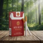 ซองบุหรี่ Red Ruby สีแดงเข้มพร้อมโลโก้สิงโตสีทอง วางบนโต๊ะไม้ในบรรยากาศป่าไม้ธรรมชาติ