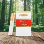 ซองบุหรี่ Liqun Red Hard สีขาวคาดแดงดีไซน์คลาสสิก วางบนโต๊ะไม้ฉากหลังป่าไม้ธรรมชาติ