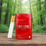 ซองบุหรี่ Dusk Premium สีแดงวางบนโต๊ะไม้ในป่าธรรมชาติ