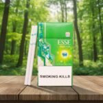 บุหรี่ ESSE Menthol Plus+ ซองสีเขียวดีไซน์ทันสมัย วางคู่กับมวนบุหรี่ซุปเปอร์สลิมบนโต๊ะไม้ฉากหลังป่าไม้ธรรมชาติ
