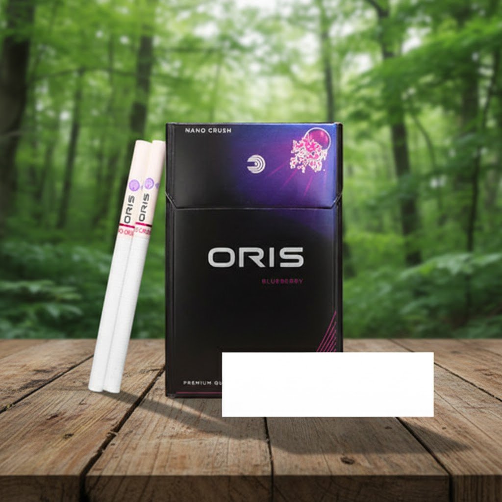 บุหรี่ Oris Nano Crush Blueberry แบบมวนนาโน 1 เม็ดบีบ รสเย็นกลิ่นบลูเบอร์รี่ วางบนโต๊ะไม้ฉากหลังป่า