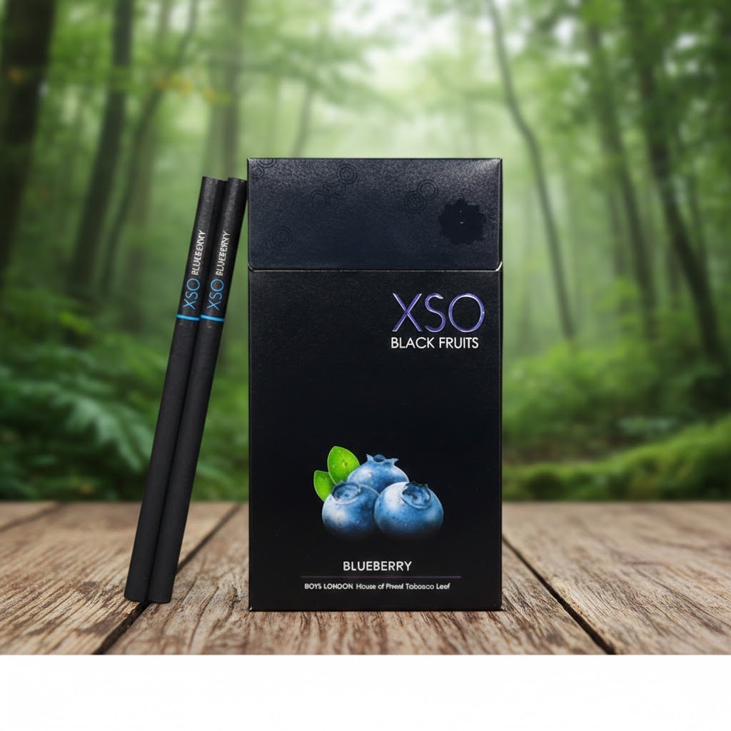 บุหรี่ XSO Blueberry ซองสีดำลายบลูเบอร์รี่ พร้อมมวนบุหรี่สีดำสนิท วางบนโต๊ะไม้ในบรรยากาศป่าธรรมชาติ
