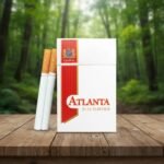 บุหรี่ Atlanta Red ซองสีขาวแถบแดง พร้อมมวนบุหรี่วางบนโต๊ะไม้ฉากหลังป่าธรรมชาติ