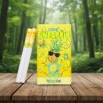 บุหรี่ Zest Pineapple ซองสีเหลืองลายกราฟิกสับปะรดใส่แว่นกันแดด พร้อมมวนบุหรี่วางบนโต๊ะไม้ฉากหลังป่า