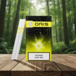 ซองบุหรี่ Oris Intense Deep Mix สีดำตัดเหลือง ดีไซน์ลายวงจรไฟฟ้า วางบนโต๊ะไม้ท่ามกลางบรรยากาศป่าสีเขียว