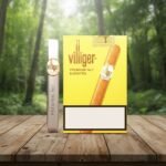 ซิการ์ Villiger Premium No.7 Sumatra กล่องสีเหลืองวางคู่กับมวนซิการ์ในซองฟอยล์สีเงินบนโต๊ะไม้ฉากหลังป่าไม้สีเขียว