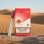 ซองบุหรี่ Oris Strawberry สีขาวแดงลายผลสตรอเบอร์รี่ วางบนท่อนไม้แห้ง ฉากหลังสันทรายสีทอง