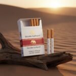 ซองบุหรี่ Golden Elephant สีขาวแถบแดง พร้อมมวนบุหรี่ วางบนขอนไม้เก่าท่ามกลางบรรยากาศพระอาทิตย์ตกในทะเลทราย