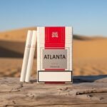 บุหรี่ Atlanta Red Premium ซองสีขาวแถบแดง พร้อมมวนบุหรี่วางบนขอนไม้ในทะเลทราย