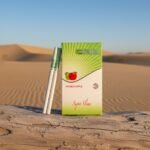 บุหรี่ Oris Double Apple ซองสีเขียวขาว ดีไซน์มวนซุปเปอร์สลิม วางบนขอนไม้ในทะเลทราย