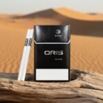 ซองบุหรี่ Oris Nano Black สีดำดีไซน์เรียบหรู วางบนท่อนไม้แห้งกลางทะเลทราย แสงแดดสีทอง